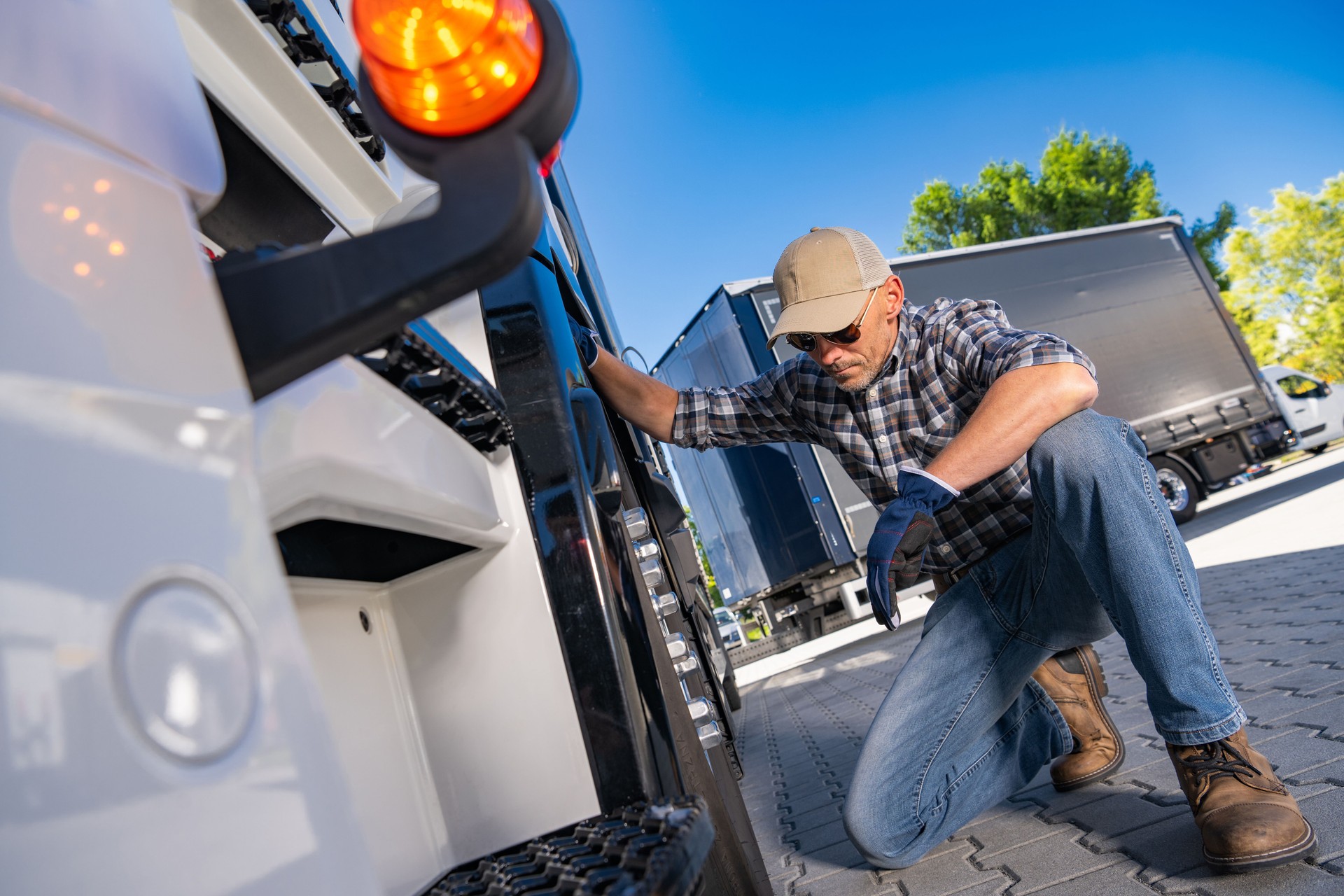 A Mechanic Checks the Rear Lights of a Truck in a Busy Repair Yard on a Sunny Afternoon